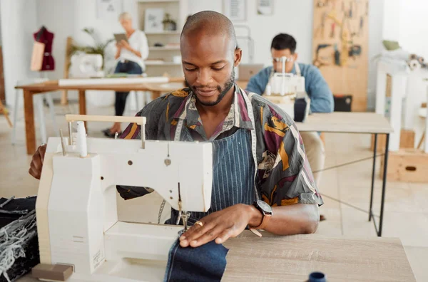 Fashion designer, young man and creative student in a workshop to sew clothes and garments. Factory worker, tailor and apprentice learning sewing machine skills in a textile and manufacturing studio.