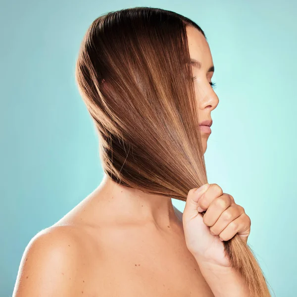 My hair feels amazing today. Studio shot of an attractive young woman posing against a blue background