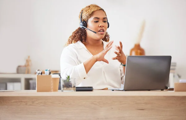 Female call center agent talking on headset while doing a video or zoom call and working in an office. Businesswoman consulting and explaining while on a call for customer sales and service support.