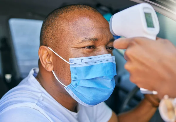 Fever, temperature and Covid test at drive through station in a car. Screening patient with protective mask with a digital thermometer. Wellness and safety of people through a pandemic.