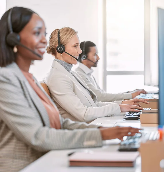 On call and ready to help. an attractive mature female call center agent wearing a headset while working in the office with her coworkers