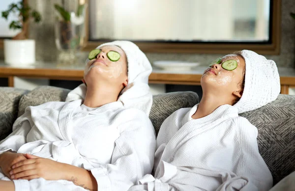 Beauty, relaxing and skincare for mother and daughter, having a spa treatment at home. Little girl and parent bonding while doing hygiene, refreshing grooming. Females with cucumber, facial mask.