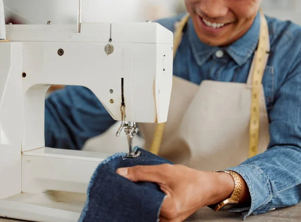 Design student, creative and worker in a studio sewing clothes and garments. Fashion student learning sewing machine skills in a textile and manufacturing studio. Happy trainee practicing his craft.