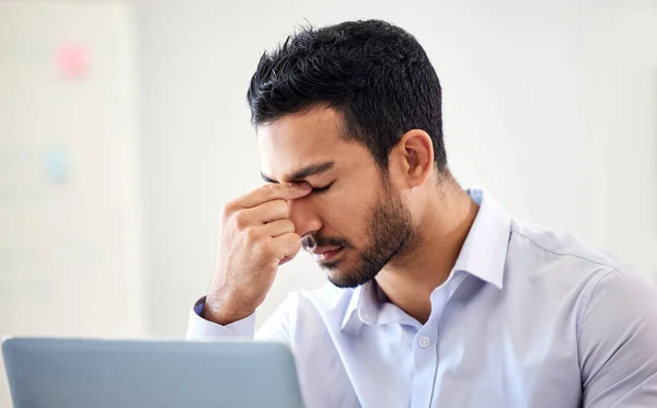 Stressed, frustrated and depressed business man suffering from a headache or migraine and struggling to meet a deadline. Overworked, irritated and annoyed male worker experiencing problems and worry.