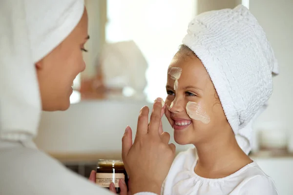 Fresh skincare, face cream and healthy skin product for mother and daughter home spa day. Fun, smiling and playful child and a parent applying moisturizer for grooming routine or sunscreen protection.