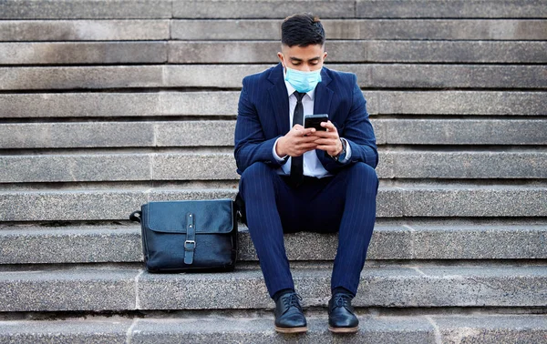 Spending my time missing you. a young businessman sitting on steps using his smartphone