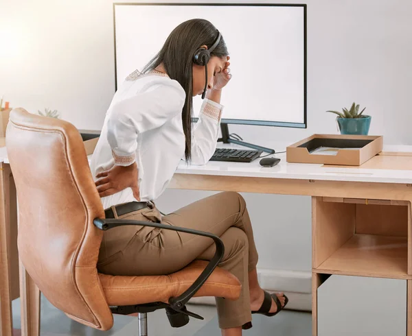 Back pain will put an end to productivity. Rearview shot of a female call center agent suffering with back pain while working on her computer in the office