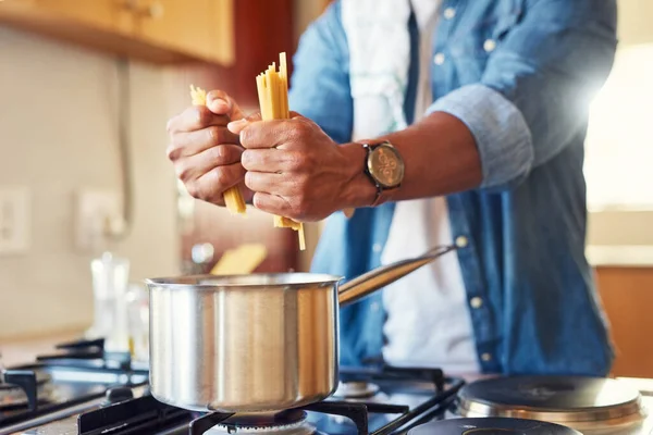 I know how to make a good spaghetti. a man breaking spaghetti before boiling it