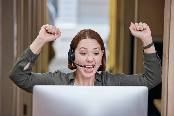 Yay You found it. a young call centre agent sitting alone in the office and celebrating a success wile using her computer