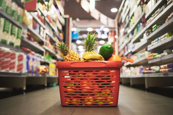 Supermarket, market or grocery store aisle with basket of quality choice, healthy fruits and vegetables. Buying retail sale items in a shopping cart. Group of consumables or food products on floor.