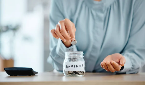 Savings, budget and economical woman putting coins in a jar at home. Closeup of woman calculating her expenses and saving money for future investment managing her house finances.