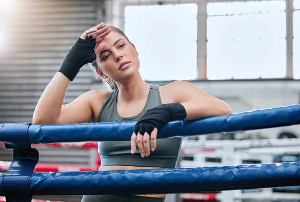 Confident, active and toned female fitness athlete in a boxing ring after a fight, match or sparring session in a gym. A healthy, fit and strong woman ready to exercise, workout and do training.