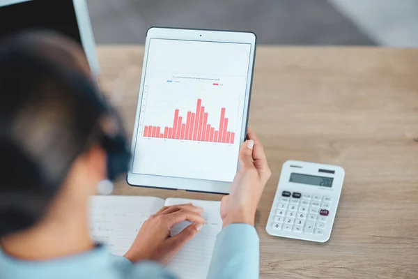 Financial advisor reading and studying finance data charts, graphs and reports on tablet in office. Above view of professional holding, analyzing and calculating profit and loss information.