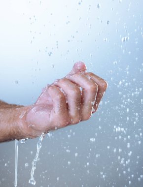 Get under those nails too. Studio shot of an unrecognizable man holding his hand out under running water against a grey background