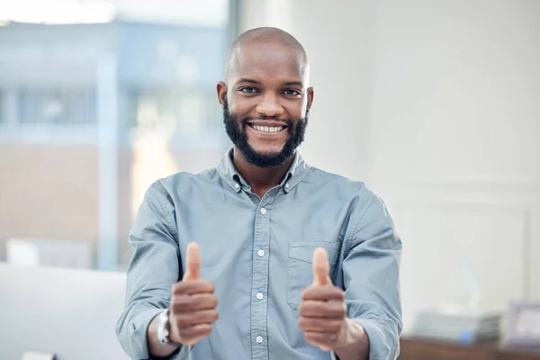 Im on the right track. a handsome young businessman standing alone in his office and making a thumbs up gesture