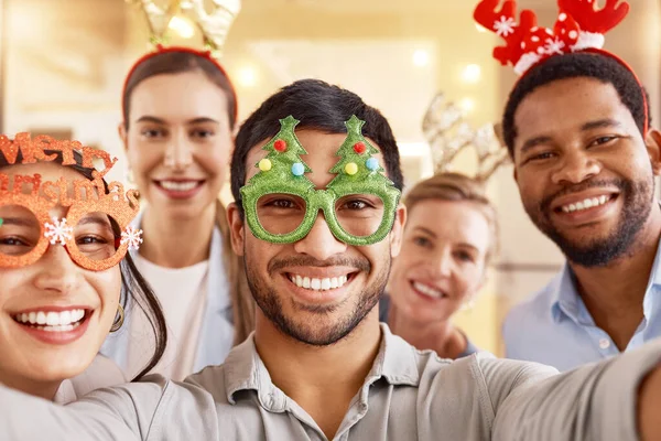 We worked hard all year, now to enjoy a little break. Portrait of a group of businesspeople taking selfies together during a Christmas party at work
