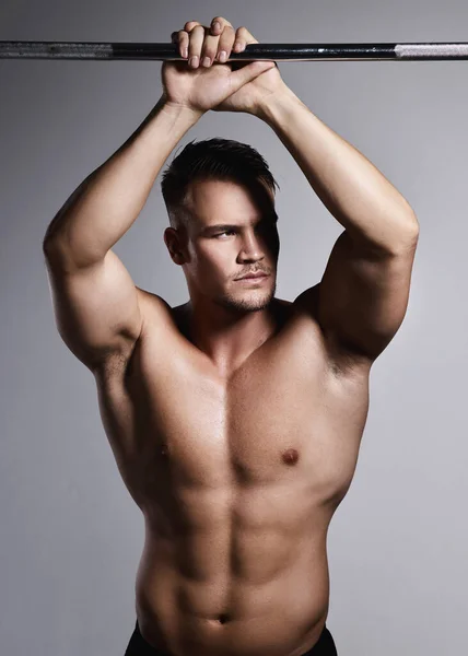 Everyone want a good-looking body but not everyone want to work for it. Studio shot of a muscular young man posing against a grey background