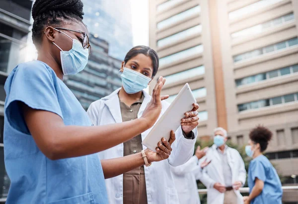 Technology changes the way the medical field operates. two young female doctors using a digital tablet in the city