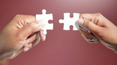 Working together to put things together. two unrecognizable businesspeople fitting puzzle pieces together in studio against a red background clipart