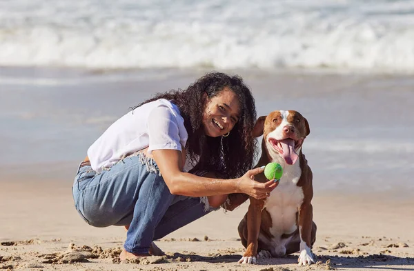 Apparently patience gets you treats. a woman playing with her pit bull at the beach