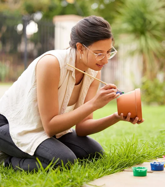 Creativity doesnt wait for that perfect moment. s young woman painting a pot in the garden at home