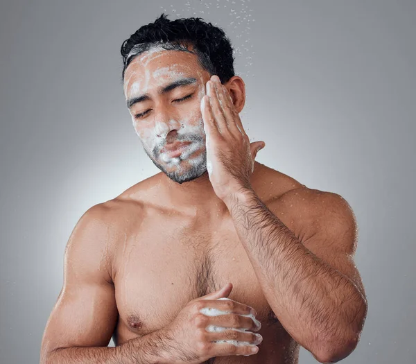 Theres nothing better than the feel of a clean face. a young man washing his face in the shower against a grey background