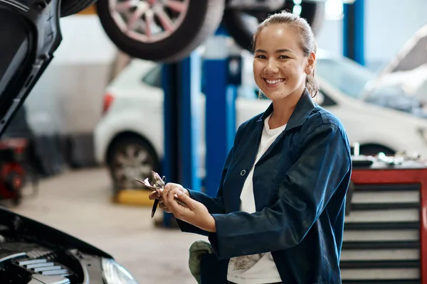 We offer both minor and major services depending on your needs. a female mechanic holding a clipboard while working in an auto repair shop