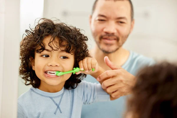 Brush your teeth everyday, To keep dentist away. a father teaching his son how to brush teeth at home