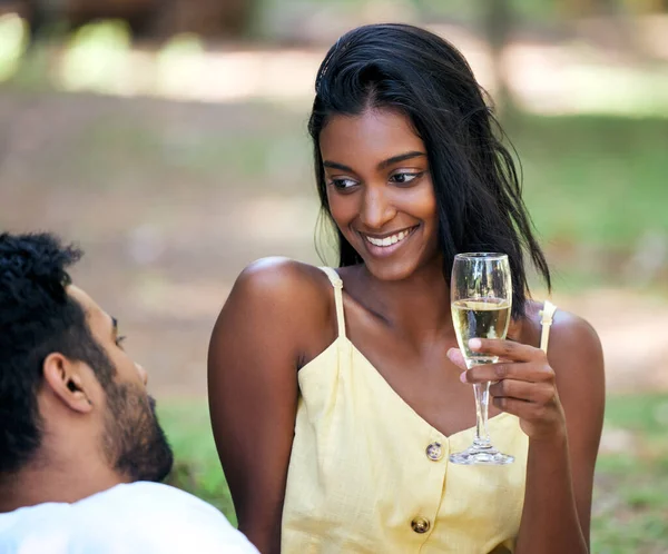 He knows just how to make me feel good. a young woman drinking champagne while on a date at the park