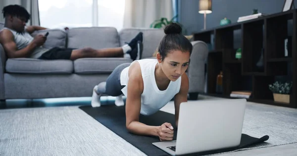 I love these virtual classes. a young woman looking at her laptop screen while exercising at home