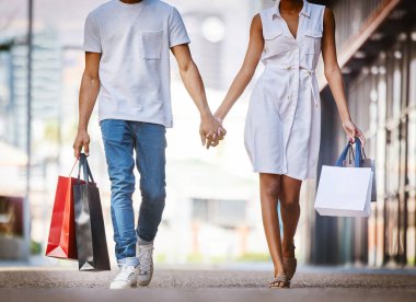 If shes having a bad day, take her shopping. a young couple walking hand in hand while holding shopping bags