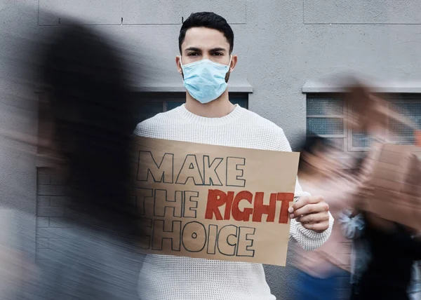 Remember to do whats best for you. a young man holding a placard at a covid vaccine protest