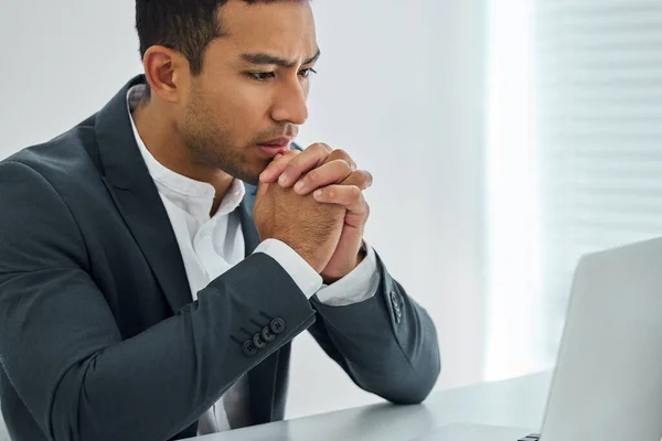 Spirit not broken, wiser than before. a businessman looking worried while using his laptop at his desk in a modern office