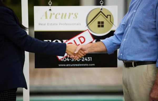 Concluding the deal with a handshake. Cropped portrait of an unrecognizable female real estate agent and her male client shaking hands in front of a sold sign in front of a newly purchased home