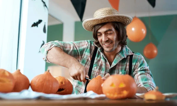 Well be eating a lot of pumpkin soon. a young man carving a pumpkin at home