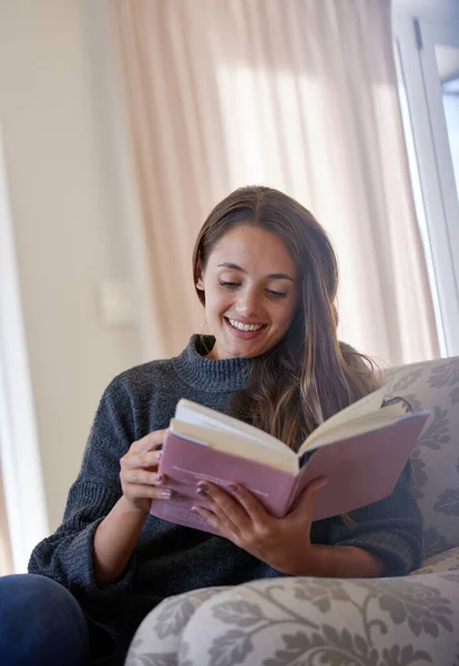 A book is a gift you can open again and again. a young woman reading a book at home