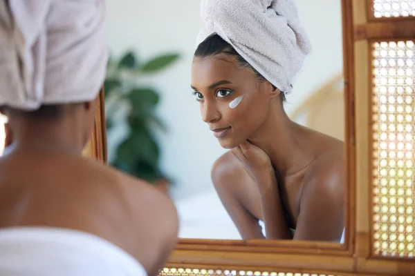 My skin looks and feels great. an attractive young woman examining her face in the mirror at home