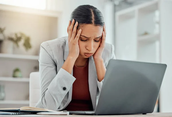 Pain, headache and stressed finance manager feeling sick, tired and worried about a financial problem at her startup company. Young and frustrated professional businesswoman working at an office.