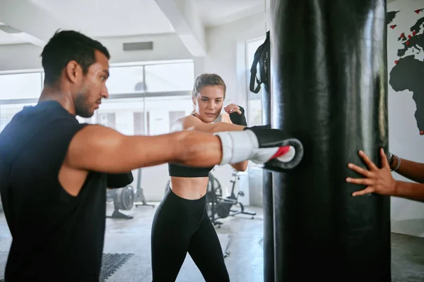 Healthy, fit and active woman boxing, training and exercising with her coach, trainer or instructor in the gym or health club. Young female boxer preparing for a fight, match or sports competition.