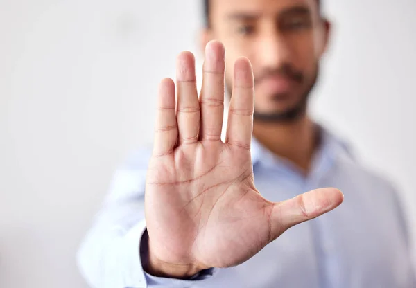 Closeup of the hand of a business man showing stop, saying no or not accepting a deal in an office at work. Male corporate worker making hand gesture not agreeing to a statement or refusing an answer.