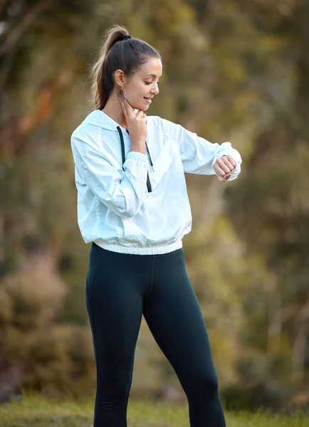 Tracking her intensity during a workout. a sporty young woman checking her pulse while exercising outdoors