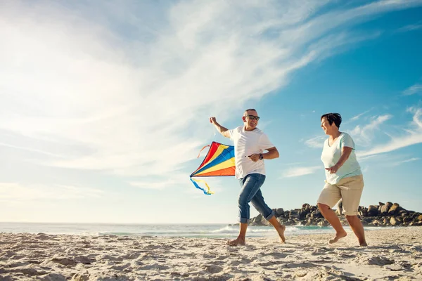 You need to let go of certain things but hold on to fun. a mature couple on the beach with a kite