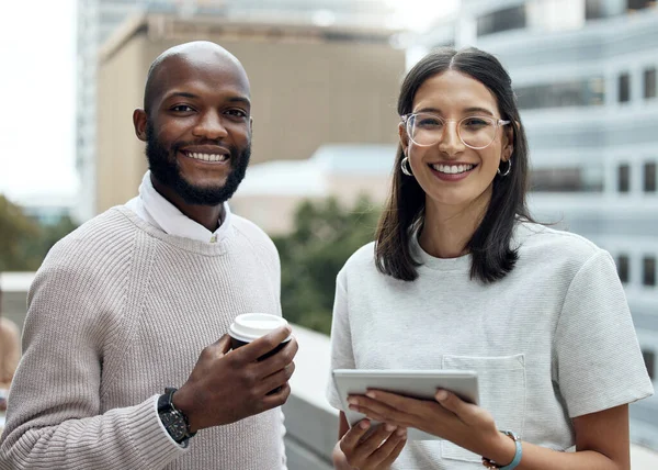 This dynamic duo are always making innovative things happen. Portrait of two businesspeople drinking coffee and using a digital tablet outside an office