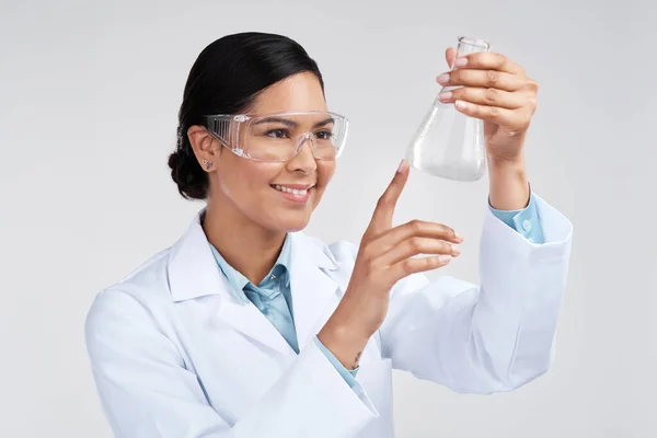 This is the reaction Im looking for. an attractive young female scientist examining a beaker filled with liquid in studio against a grey background