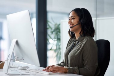 We have a team of experts waiting for your call. a woman wearing a headset while looking at her desktop in a call centre