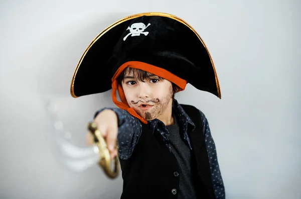 Can you tell that this a costume. a little boy wearing a pirate costume against a white background