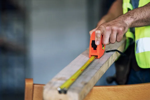 The rest dont measure up to him. a builder using a measuring tape at a construction site