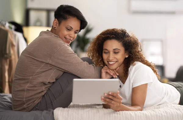 I want to hold your hand at 80. a young lesbian couple using a tablet while relaxing in their bedroom