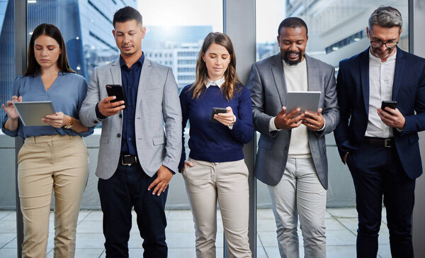 Technology makes it easier to find new clients. a group of businesspeople using digital devices in an office