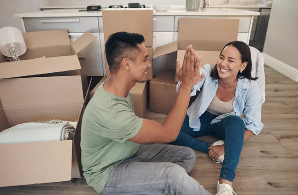 We bought the house of our dreams. a couple sharing a high-five while moving into their new home